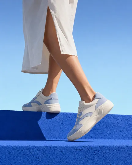 DTC sneaker brand creative: worn mid-stride on a blue step.