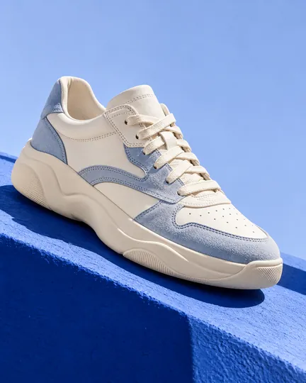 DTC sneaker brand creative: a light blue everyday sneaker on a cobalt step.